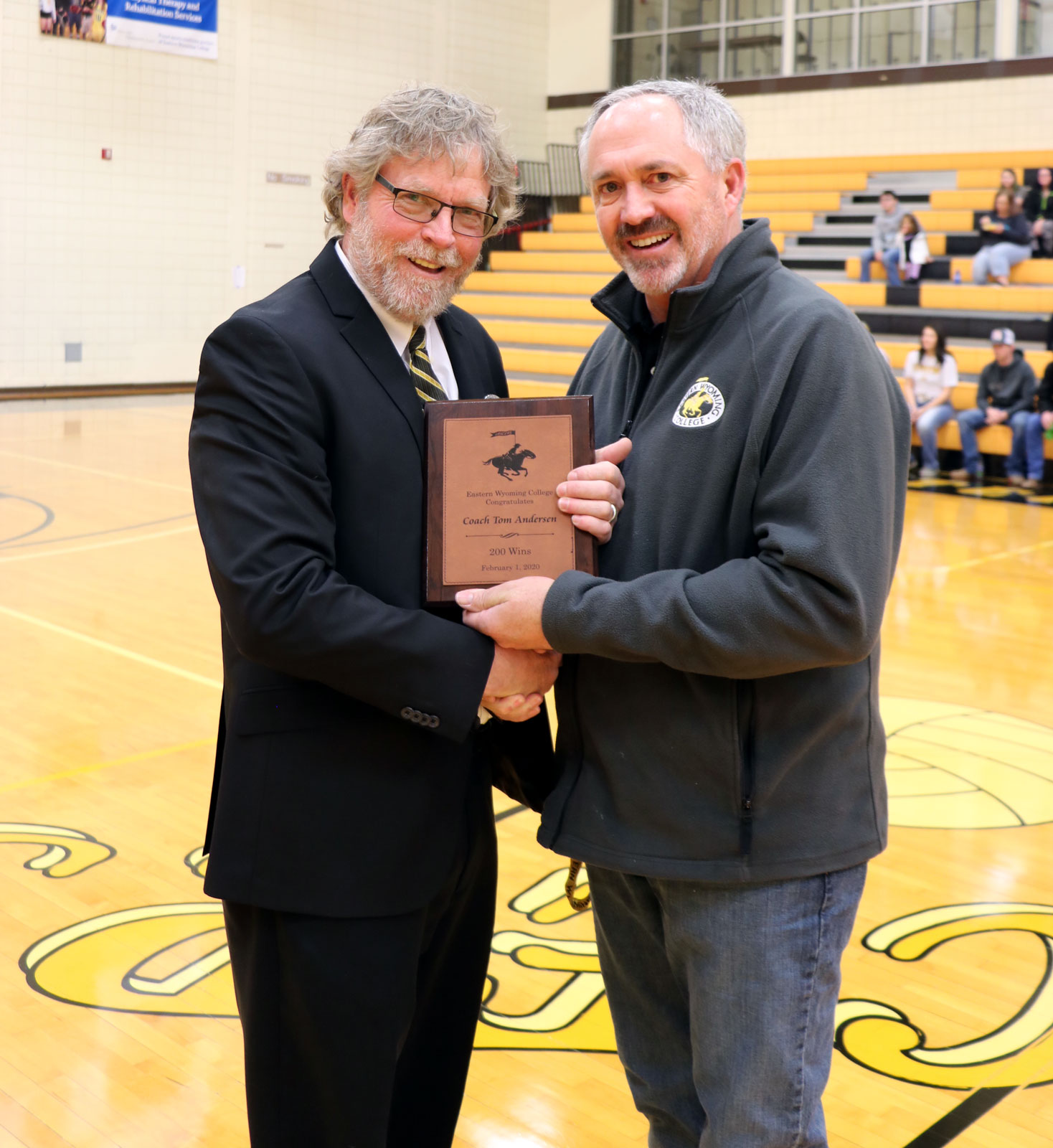 Left to right: Tom Andersen receives a plaque from Roger Humphrey, Vice President for Student Services commemorating his 200th win.