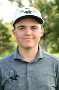 A young man wearing a white EWC Golf cap and a gray polo shirt with a horse and rider logo, standing outdoors on a golf course with green trees in the background.