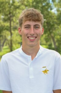 A young man wearing a white polo shirt with a yellow horse logo on the chest.