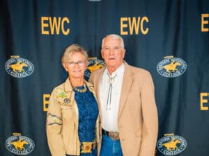 An older couple standing in front of an Eastern Wyoming College backdrop.