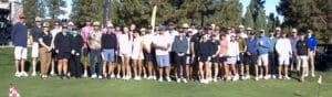 A large group of people in golf attire standing together on a putting green.